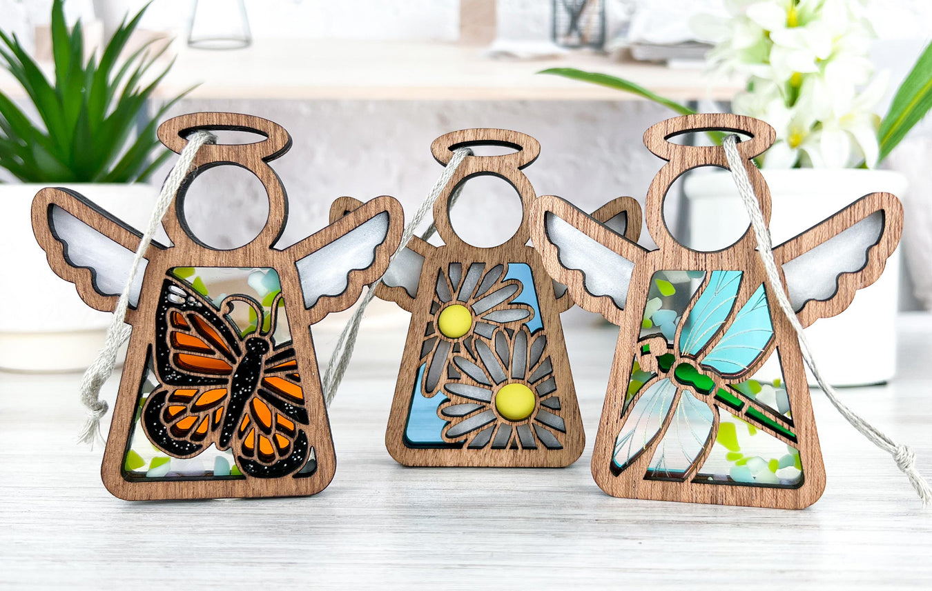 Three unique Mother's Angels® ornaments with intricate woodwork and designs inspired by stained glass, featuring a monarch butterfly, daisy, and dragonfly, making them unique Mother's Day gifts that celebrate craftsmanship and beauty.
