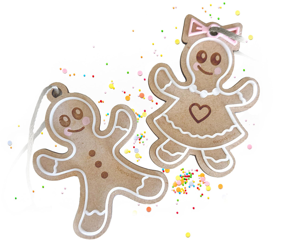 Two gingerbread cookie-shaped decorations, one boy and one girl, on a white background with colorful sprinkles.