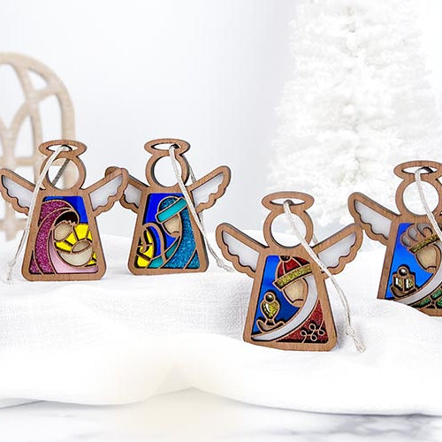 Handcrafted Mother’s Angels® Christmas Nativity scene featuring seven angel ornaments, including Mary, Joseph, and baby Jesus, displayed on a festive holiday table.