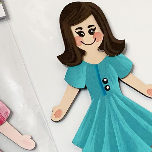 Cartoon-style paper dolls called Dejadoodles with different hairstyles and clothing on a white background