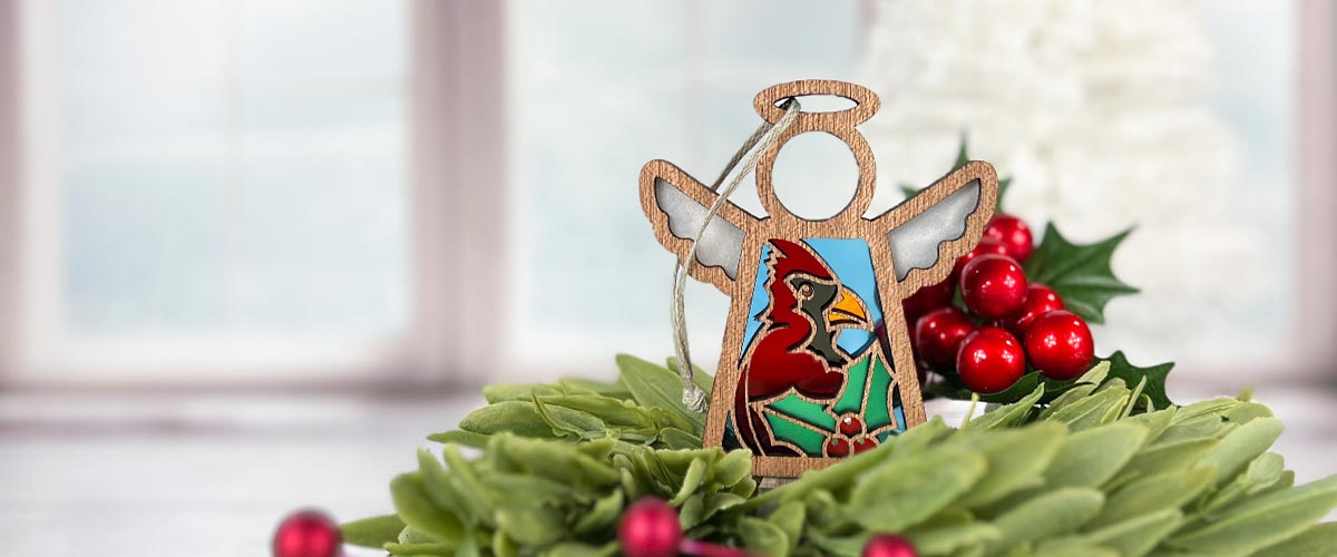 A Winter Cardinal Mother’s Angels® ornament displayed in the center of a miniature holiday wreath.
