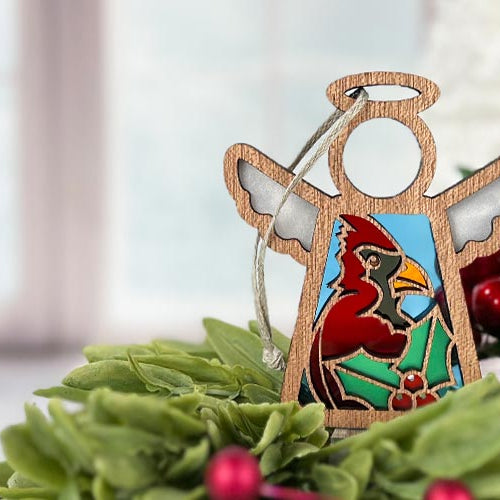 Wooden angel ornament with a cardinal design on a green leafy background