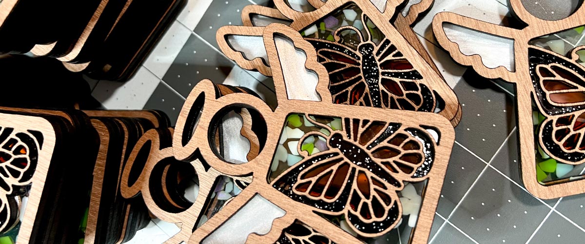 Wooden butterfly Mother’s Angels® ornaments fully assembled on a cutting mat background.