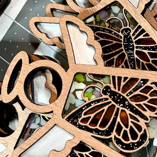 Wooden butterfly Mother’s Angels® ornaments fully assembled on a cutting mat background.