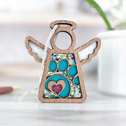 Forged Flare® rainbow bridge gift, a wooden Mother’s Angels® paw print angel ornament with colorful design, displayed on a white surface to honor your pet.