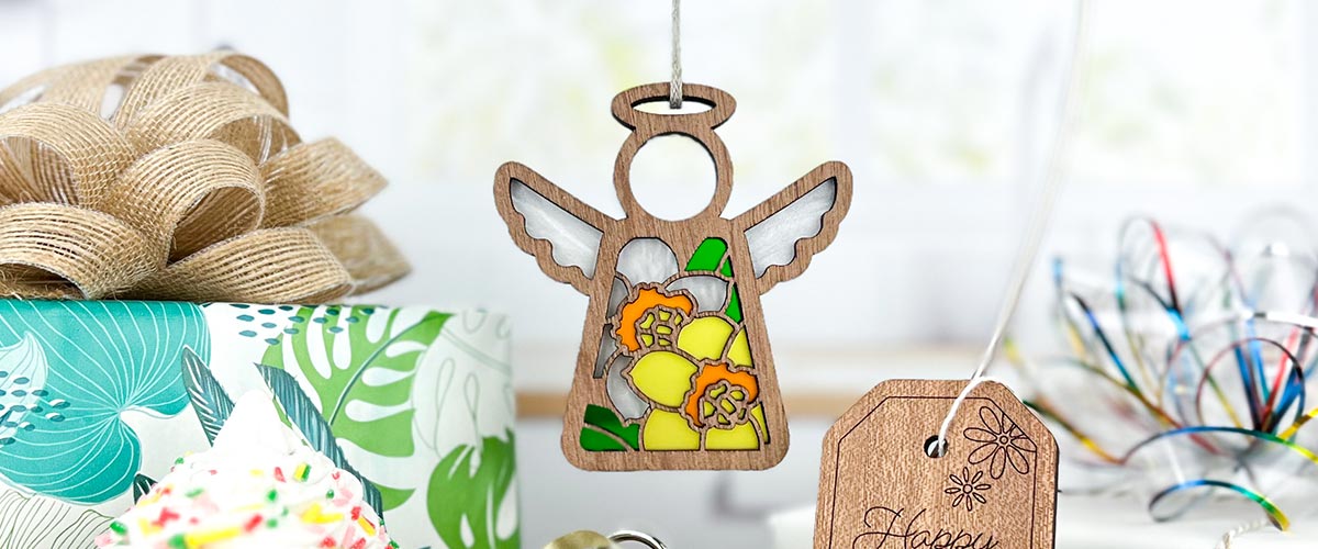 Wooden angel ornament with floral daffodil birth flower design on a blurred background.
