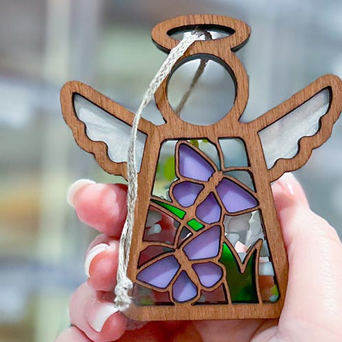 Forged Flare® angel ornaments with vibrant purple butterfly designs, handcrafted in Texas and held gently for a heartfelt display of Mother’s Angels® keepsakes.