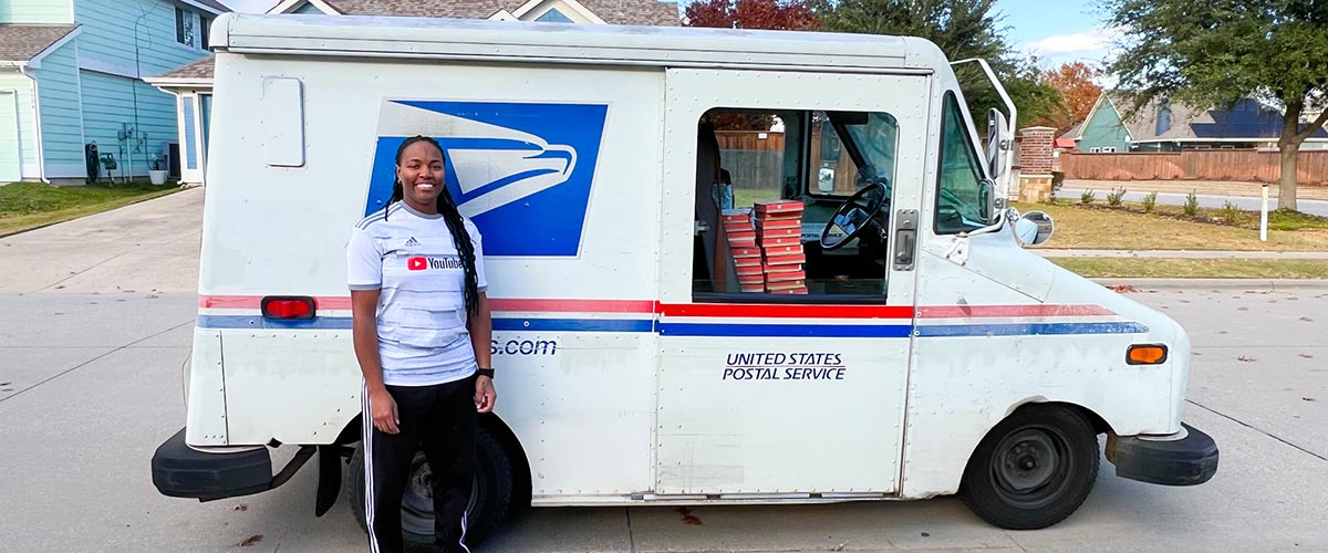 Postal worker standing next to a United States Postal Service vehicle in a residential area