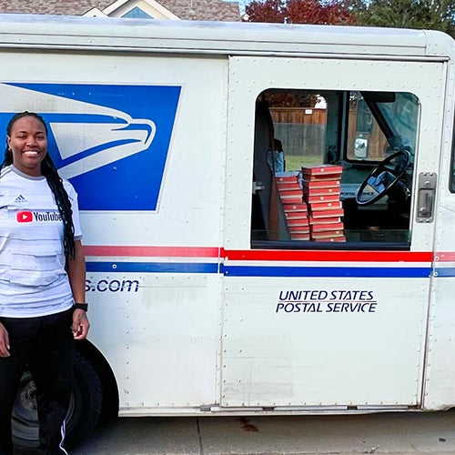 Postal worker standing next to a United States Postal Service vehicle in a residential area
