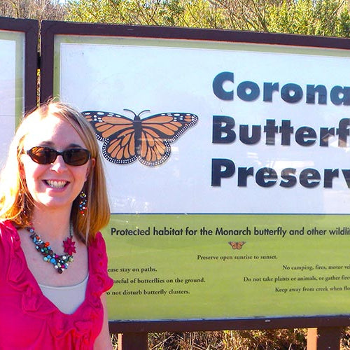 Jen standing in front of a 'Coronado Butterfly Preserve' sign with butterfly graphics.