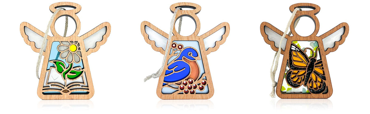 Three angel ornaments with charming designs on a white background. The first shows a white daisy flower springing from the inside pages of a book that is perfect for book club gifts, the second shows a bluebird sitting on a twig of red berries against a light blue background, and the third is a beautiful monarch butterfly ornament.