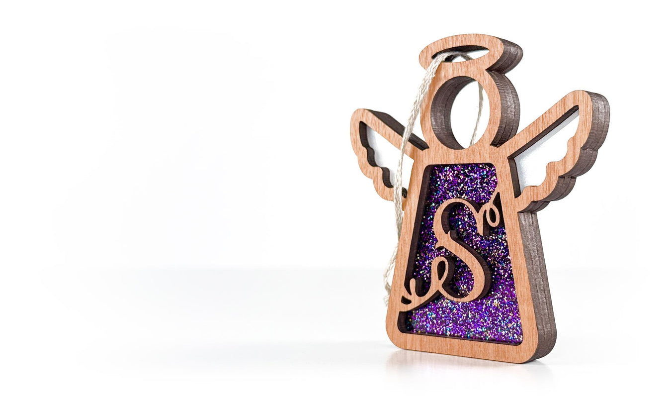 Wooden angel ornament with purple glittery body on a white background