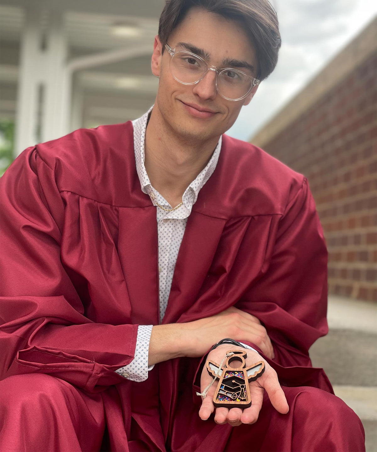 A recent graduate holding a graduation Mother’s Angels® ornament gift.