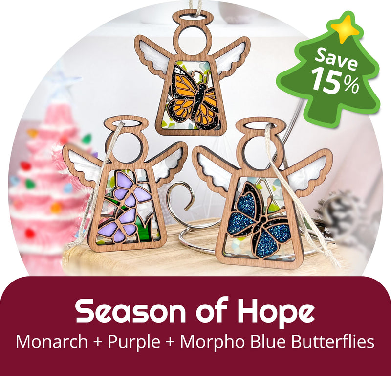 Two wooden Mother's Angels® 3.5" angel figurines (Daisy, Sunflower) by Forged Flare® from the Holiday Cheer 2-Piece Bundle are displayed with a "Save 15%" holiday sale tag, festive decor, and a blurred pink Christmas tree in the background.