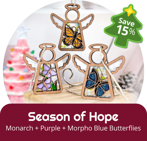 Two wooden Mother's Angels® 3.5" angel figurines (Daisy, Sunflower) by Forged Flare® from the Holiday Cheer 2-Piece Bundle are displayed with a "Save 15%" holiday sale tag, festive decor, and a blurred pink Christmas tree in the background.