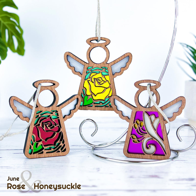 The Forged Flare® Mother's Angels® Red Rose Ornament features a stained glass-style angel figurine (3.5" H) with unique imperfections, displaying a red rose design and “June Rose & Honeysuckle” in the corner.