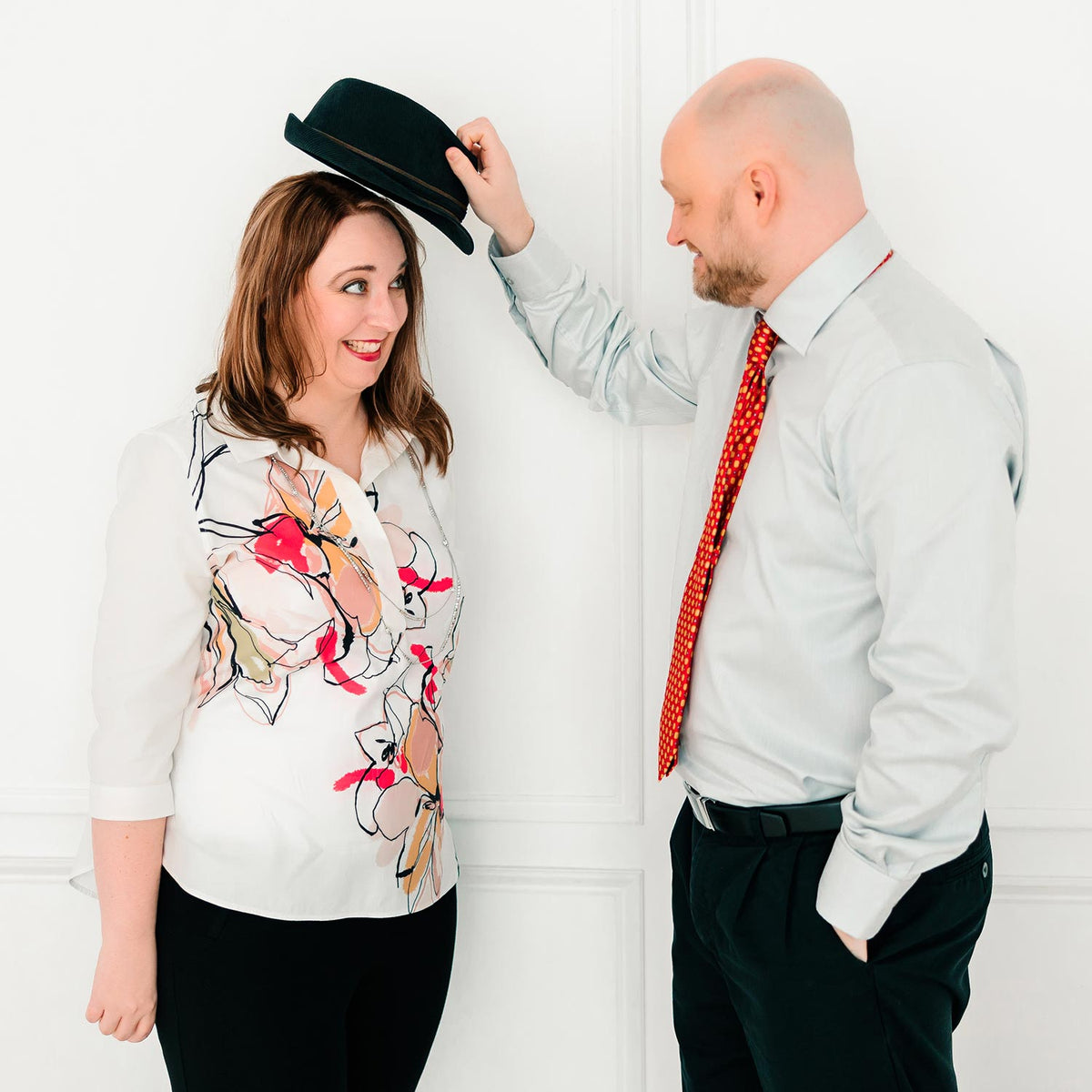 Chris placing a hat on Jen's head.