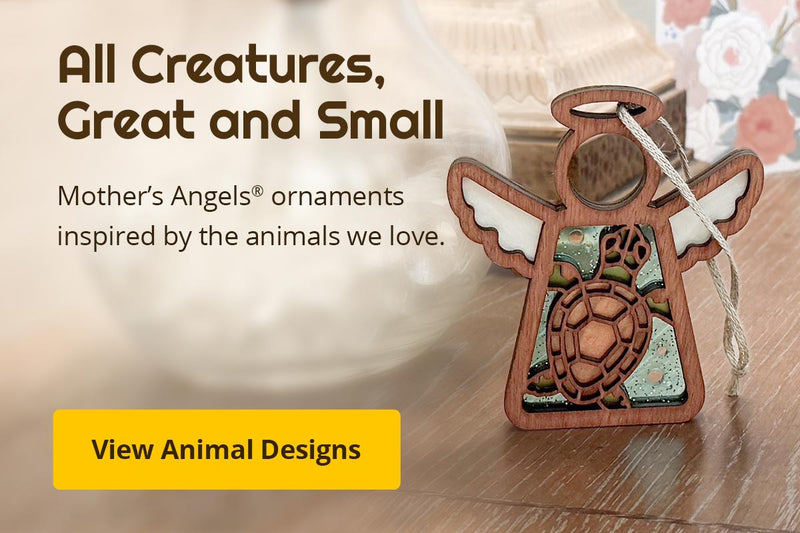 A sea turtle angel ornament on a bedside table. Text reads: All Creatures, Great and Small. Mother’s Angels® ornaments inspired by the animals we love. View Animal Designs. 