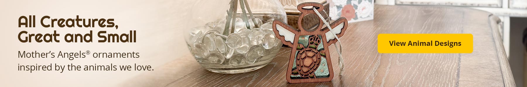 A sea turtle angel ornament on a bedside table. Text reads: All Creatures, Great and Small. Mother’s Angels® ornaments inspired by the animals we love. View Animal Designs. 