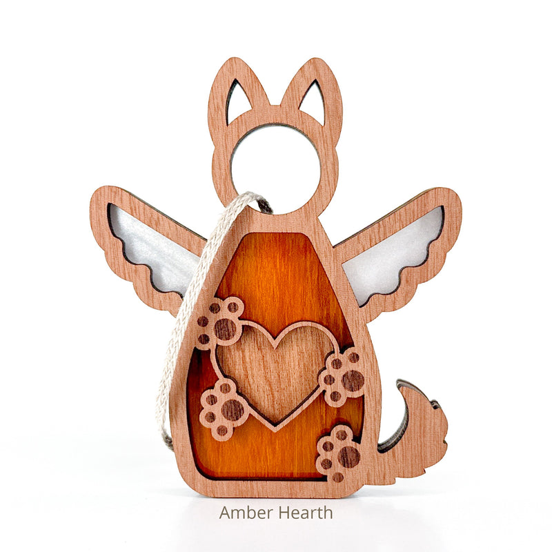 The Forever By My Side Dog Angel Ornament by Forged Flare® features a wooden angel with wings, pointed ears, and tail. It has a heart cutout with paw prints, and a string. Text reads "Amber Hearth".