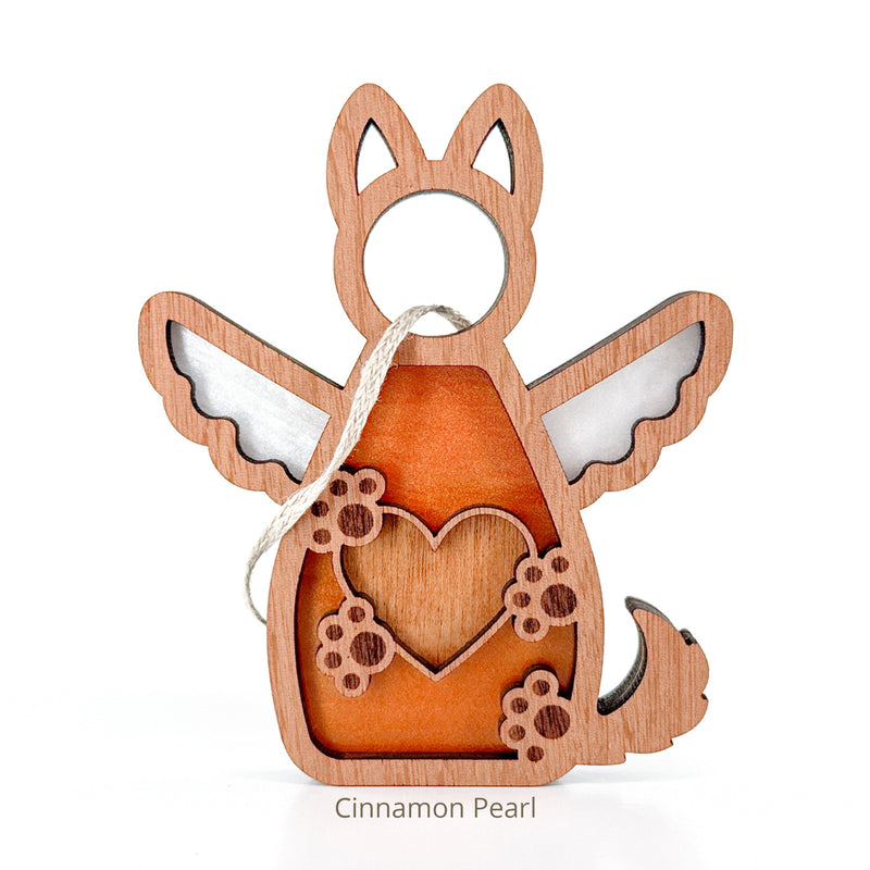 The Forged Flare® Forever By My Side Dog Angel Ornament features a dog with wings, tail, heart and paw prints, and a hanging loop—perfect as a dog mom gift. Text reads "Cinnamon Pearl".