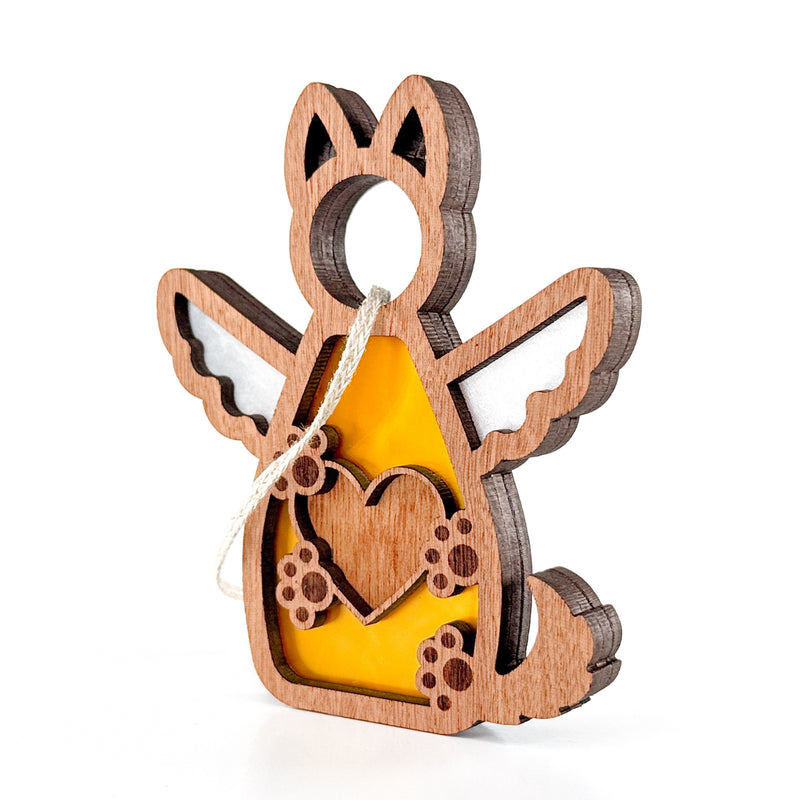 The Forged Flare® Forever By My Side Dog Angel Ornament features a winged dog with a heart cut-out, paw print accents, and a yellow background. This charming gift for dog lovers hangs easily by its attached white string.