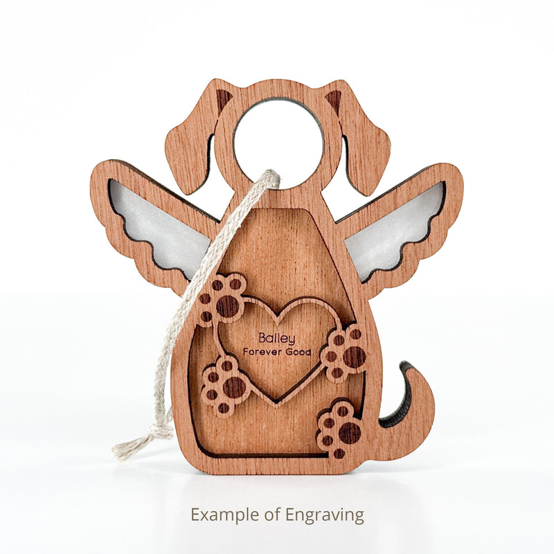 The Forged Flare® Forever In My Heart Dog Angel Ornament features a wooden dog with angel wings, heart, and flower cutouts. Engraved with "Bailey Forever Good." Includes hanging string; Text reads "Example of Engraving".