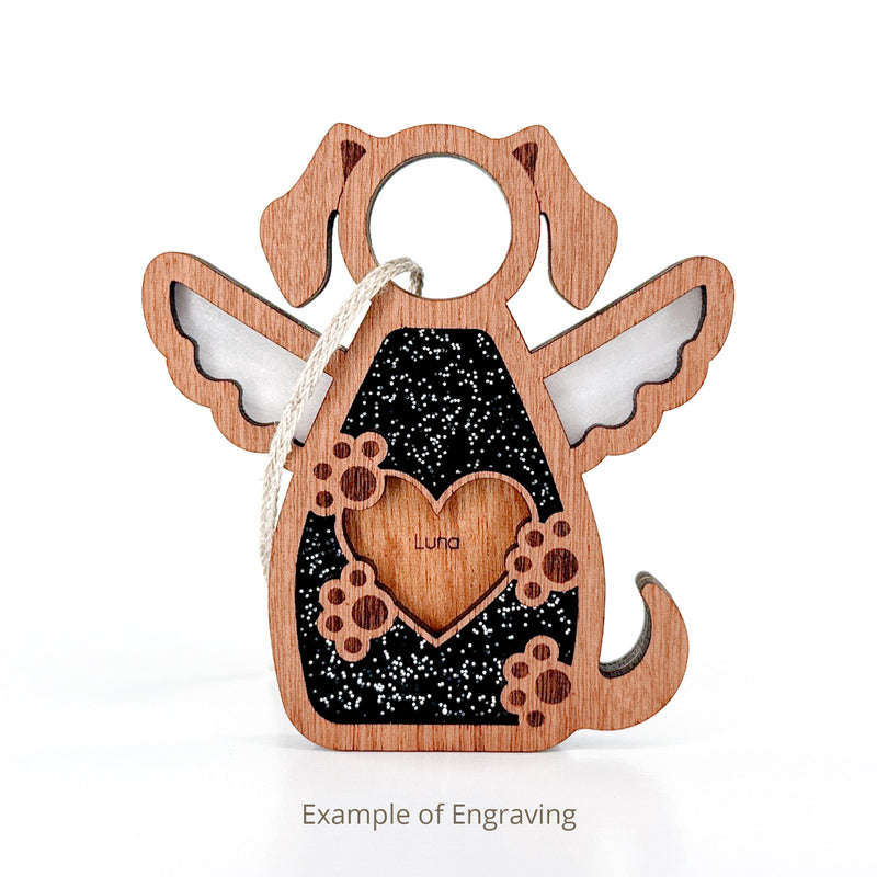 The Forged Flare® Forever In My Heart Dog Angel Ornament features a dog-shaped design with wings, "Luna" heart cutout, paw prints, and a white hanging loop—ideal as a personalized pet ornament or meaningful dog lover gift. Text reads "Example of Engraving".
