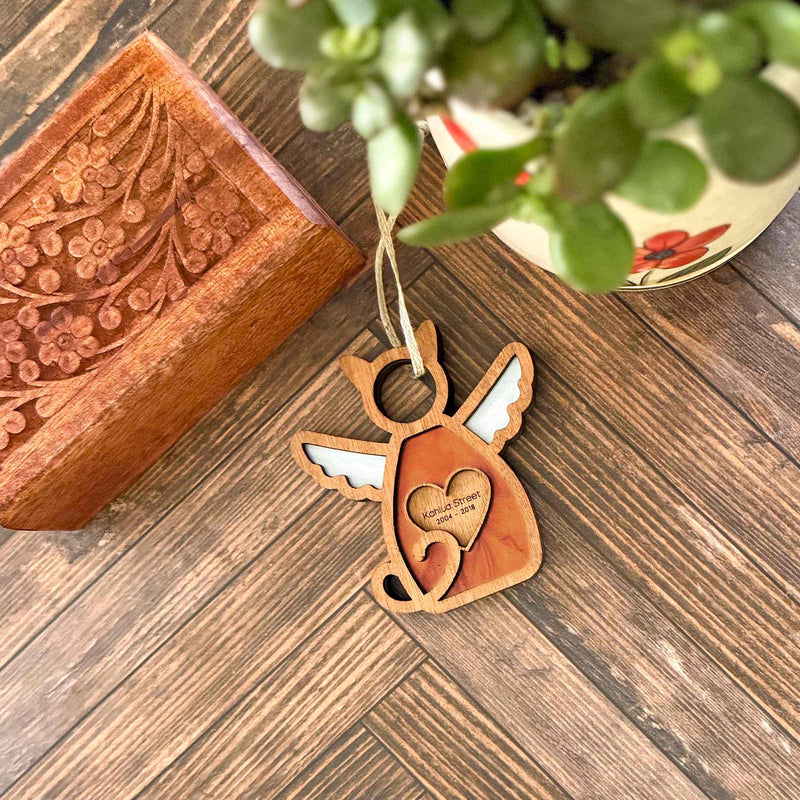 The Forged Flare® Forever Loved Cat Angel Ornament for Charity features white wings and a heart reading "ALWAYS LOVED, NEVER FORGOTTEN"—a perfect personalized pet ornament or cat memorial.