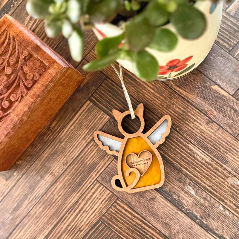 The Forged Flare® Forever Loved Cat Angel Ornament for Charity is a wooden cat-shaped memorial with wings and a heart, engraved with “watching over you”—a heartfelt keepsake for honoring your beloved pet.