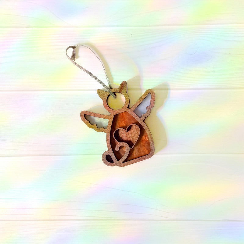 The Forged Flare® Forever Loved Cat Angel Ornament for Charity features heart cutouts and a hanging string, touched by pastel rainbow light—perfect as a custom cat ornament or thoughtful cat memorial.