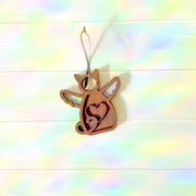 The Forged Flare® Forever Loved Cat Angel Ornament for Charity features a wooden angel with wings and a heart cutout, hanging on a string against a pale, rainbow backdrop—an ideal keepsake to honor your cat’s memory.