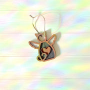 The Forged Flare® Forever Loved Cat Angel Ornament for Charity features a winged cat with a heart cutout, hanging from a string on a pastel rainbow wooden background—perfect as a personalized pet ornament or heartfelt cat memorial.