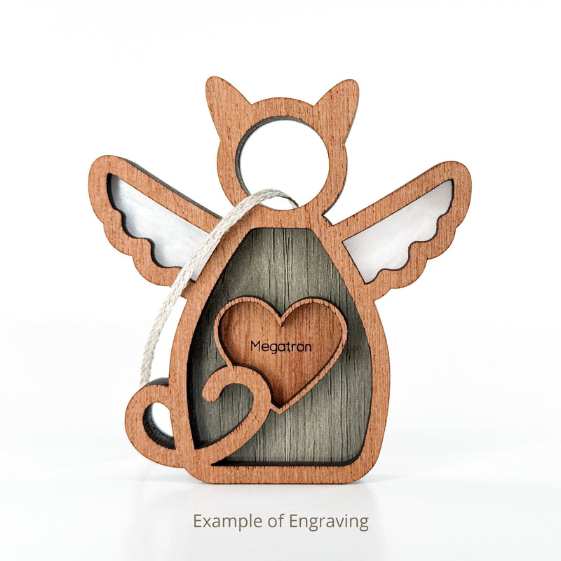 Forever Loved Cat Angel Ornament for Charity by Forged Flare® features a wooden angel-shaped cat with wings, heart cutout engraved “Megatron,” curled tail, and hanging loop. Example of Engraving text below. White background.
