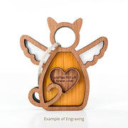 The Forged Flare® Forever Loved Cat Angel Ornament for Charity is a wooden, cat-shaped hanging ornament with wings, a heart and tail design, and sample engraving: "Waffles McFluff Forever Loved." Example of Engraving shown below.