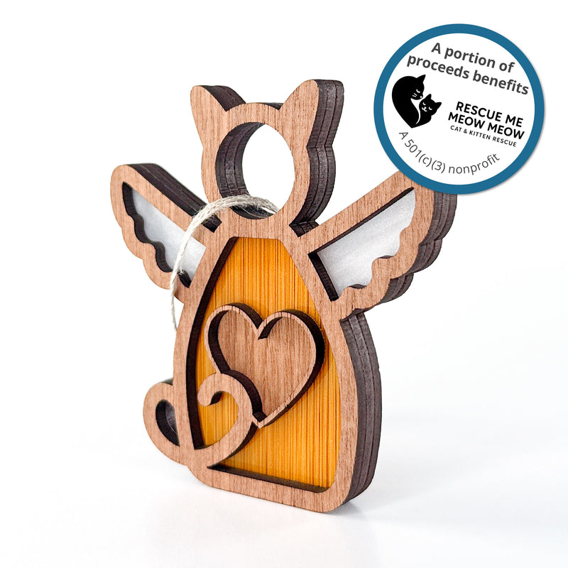 The Forged Flare® Forever Loved Cat Angel Ornament is a handcrafted cat-shaped keepsake with wings and heart. Sticker text reads "A portion of proceeds benefits Rescue Me Meow Meow Cat and Kitten Rescue. A 501c3 nonprofit".
