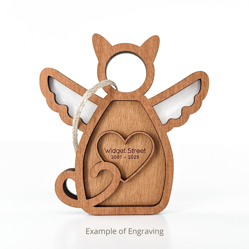 The Forged Flare® Forever Loved Cat Angel Ornament for Charity features angel wings, a halo, an engraved heart ("Widget Street 2007 – 2025"), a hanging string, and "Example of Engraving" text—perfect as a cat memorial.