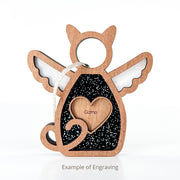 The Forever Loved Cat Angel Ornament for Charity by Forged Flare® features a wooden cat with black and white wings, curled tail, and a heart engraved with "Gizmo." A unique keepsake, the text below shows "Example of Engraving.