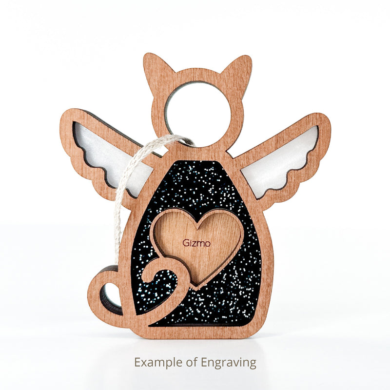 The Forever Loved Cat Angel Ornament for Charity by Forged Flare® features a wooden cat with black and white wings, curled tail, and a heart engraved with "Gizmo." A unique keepsake, the text below shows "Example of Engraving.