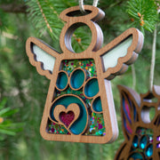 The Forged Flare® Paw Print Ornament with Imperfections is a heartfelt 3.5" Mother's Angels® keepsake, featuring a glittery heart and angel figurine, perfect as a cheerful pet memorial gift with its colorful confetti background.
