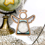 The Forged Flare® Mother's Angels® Sand Dollar Ornament with Imperfections is a 3.5" handcrafted angel figurine featuring blue and white accents, a sand dollar centerpiece, and comes with a globe, brass stand, and decorative netting.