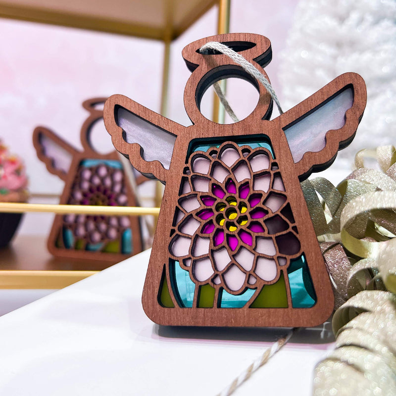 The Forged Flare® Chrysanthemum Ornament with Imperfections is a 3.5" tall Mother's Angels® handcrafted wooden angel figurine with stained glass wings and a colorful floral design, inspired by chrysanthemum centerpieces.