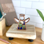 The Forged Flare® Luna Moth Ornament is a 3.5" Mother's Angels® figurine with white wings and a blue, brown, and green design. It stands on a wooden base and includes a hanging string, perfect as a Christmas tree ornament or decor piece.
