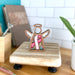 A decorative pink ribbon angel ornament stands on a cutting board, embodying the spirit of breast cancer awareness.