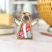 A pink ribbon angel ornament on a marble surface, a beacon of support and awareness for breast cancer.