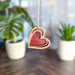 Unique Mother's Day gift of a wooden heart ornament, with a sparkling red center, hanging delicately as a symbol of love and appreciation for Mom.