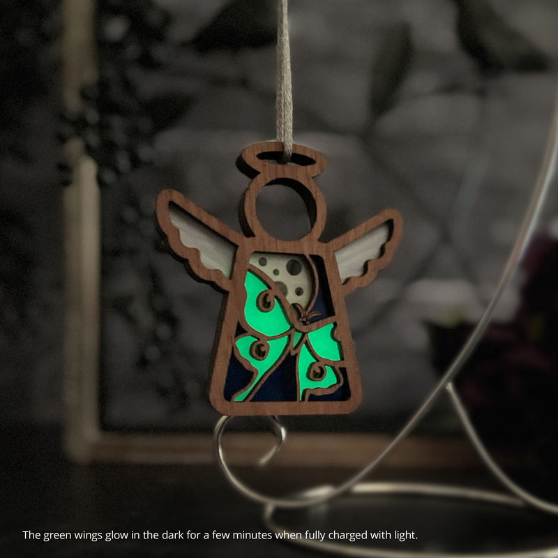 The Luna Moth Ornament by Forged Flare® is a 3.5" wooden angel figurine with glowing green and blue wings, perfect as a unique Christmas tree ornament from the Mother's Angels® collection.