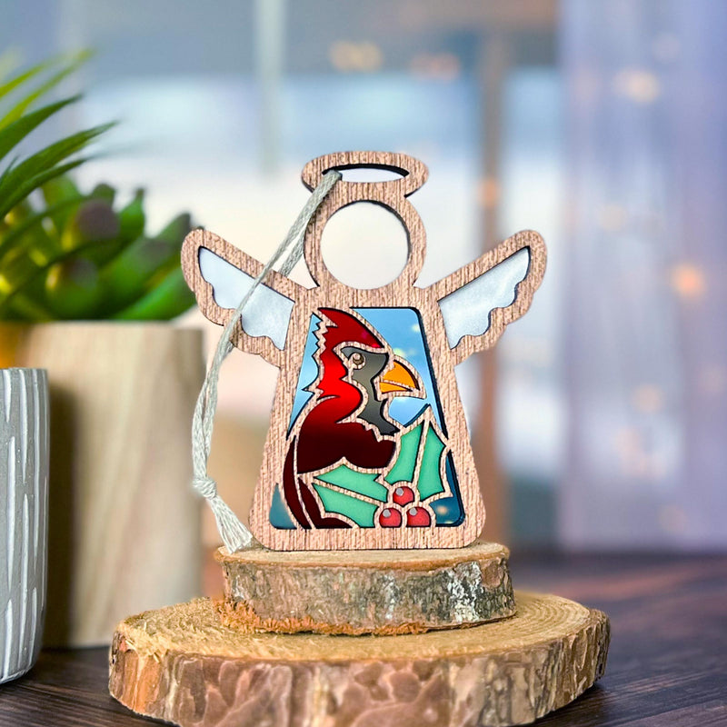 The Forged Flare® Mother's Angels® Winter Cardinal Ornament is a 3.5" handcrafted angel figurine with stained glass, cardinal, and holly leaves—an exquisite collectible centerpiece for your décor, even with its unique imperfections.