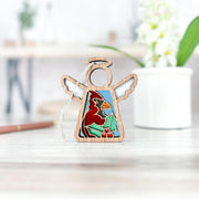 The Forged Flare® Winter Cardinal Ornament with Imperfections is a 3.5" handcrafted Mother's Angels® figurine featuring a painted red cardinal and holly—a charming collectible for your angel collection.