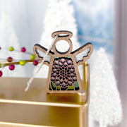 The Forged Flare® Chrysanthemum Ornament with Imperfections is a 3.5" handcrafted Mother's Angels® wooden angel figurine featuring a cut-out flower design, displayed on gold with blurred white trees and red berries in the background.